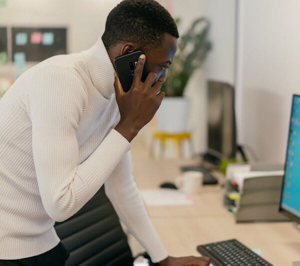Cybercriminalité au Togo - homme au téléphone devant un ordinateur, victime potentielle d'arnaque en ligne