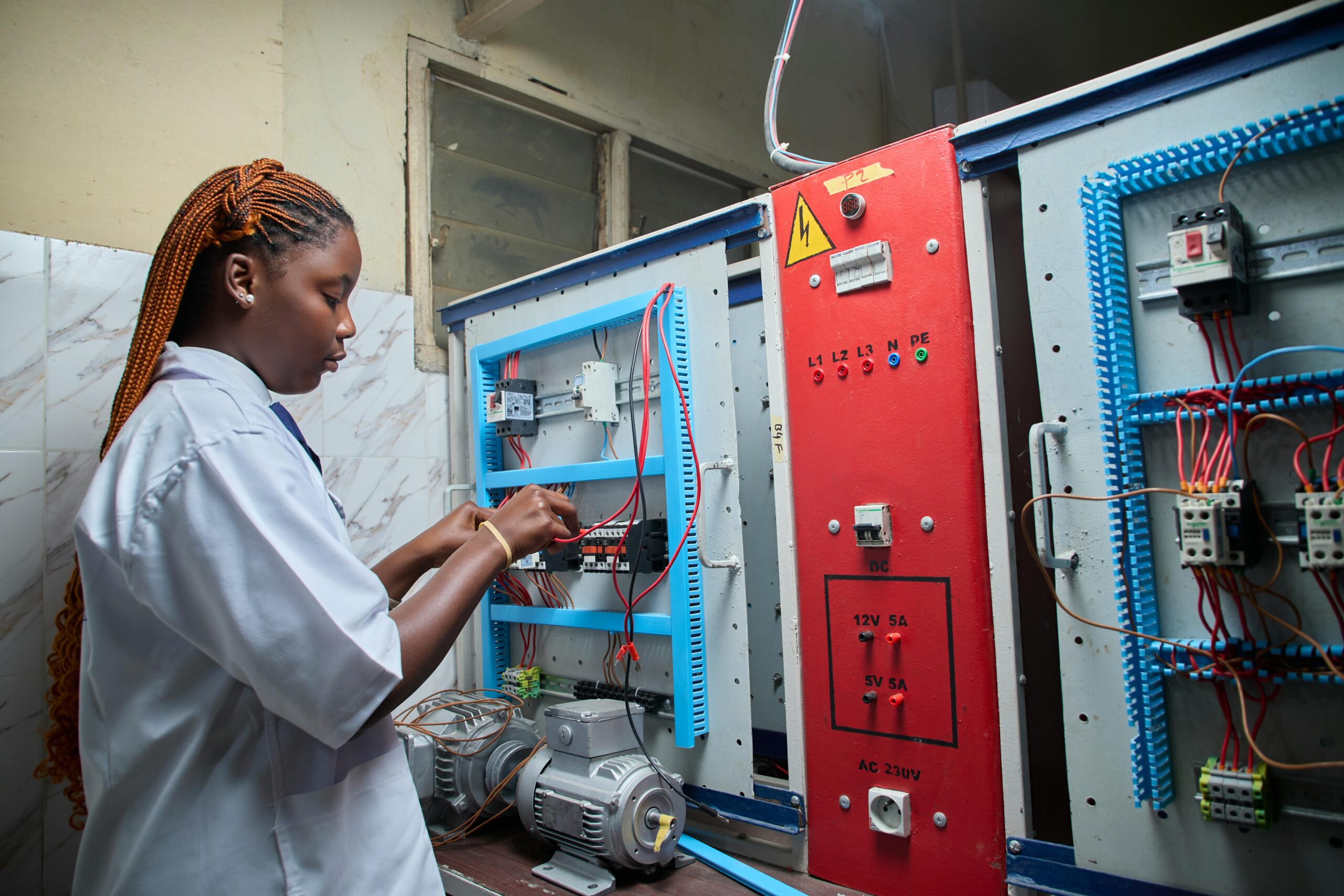 Technicienne africaine en blouse travaillant sur une armoire électrique