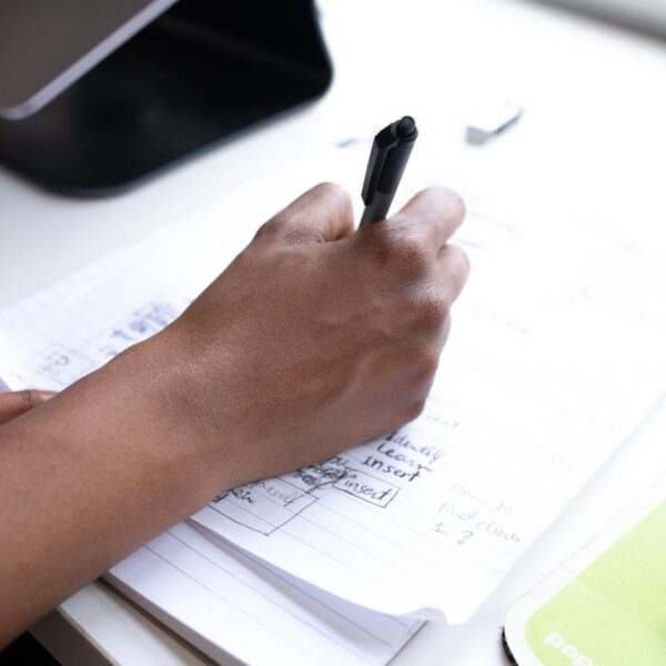 recouvrement créances OHADA Togo : main rédige documents comptables sur bureau