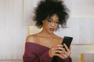 Arnaque mobile money au Togo : une femme consulte un SMS suspect sur son smartphone