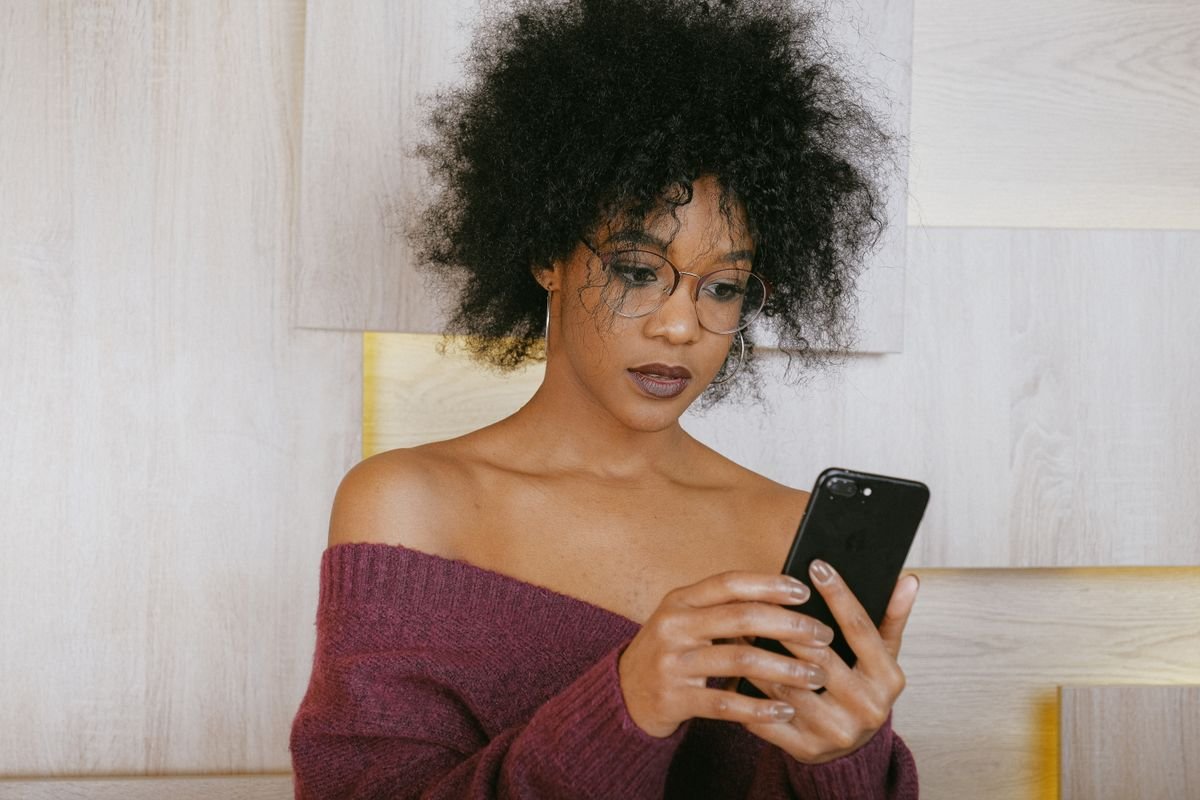 Arnaque mobile money au Togo : une femme consulte un SMS suspect sur son smartphone