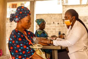 Assurance maladie universelle Togo : une soignante mesure la tension d une femme agee lors d une consultation en clinique communautaire