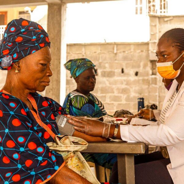 Assurance maladie universelle Togo : une soignante mesure la tension d une femme agee lors d une consultation en clinique communautaire