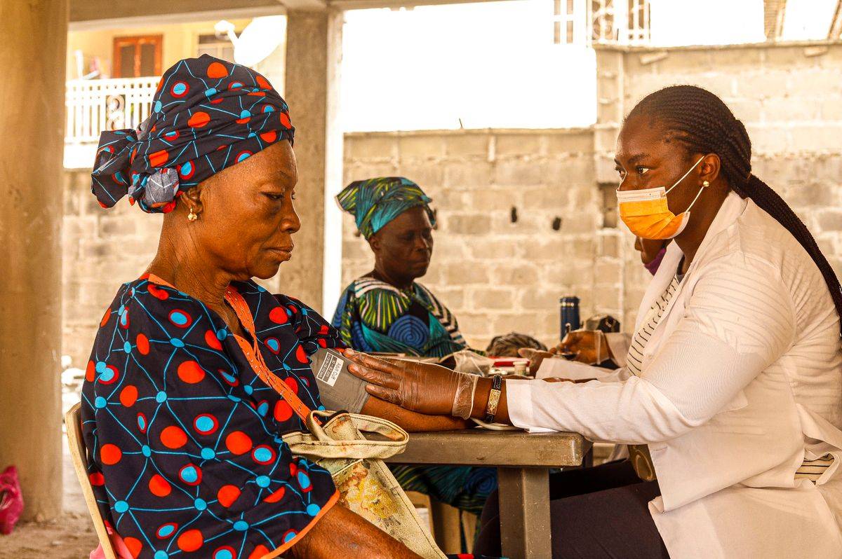 Assurance maladie universelle Togo : une soignante mesure la tension d une femme agee lors d une consultation en clinique communautaire