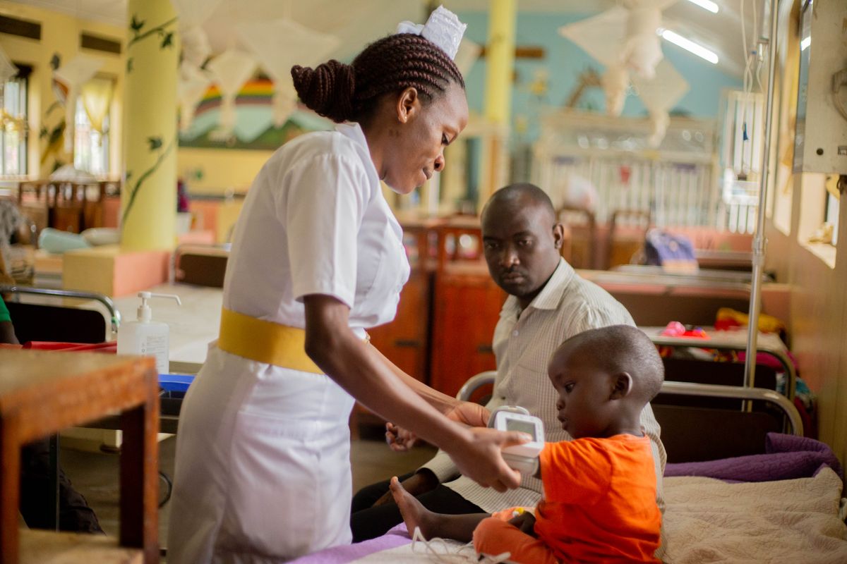 Assurance maladie universelle Togo : une infirmière soigne un enfant hospitalisé auprès de son père, l'AMU couvrant aussi la famille de l'assuré