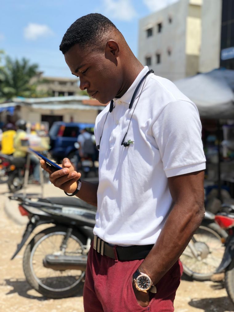 Contrat par WhatsApp au Togo : un jeune commerçant relit ses messages devant les motos d un marché