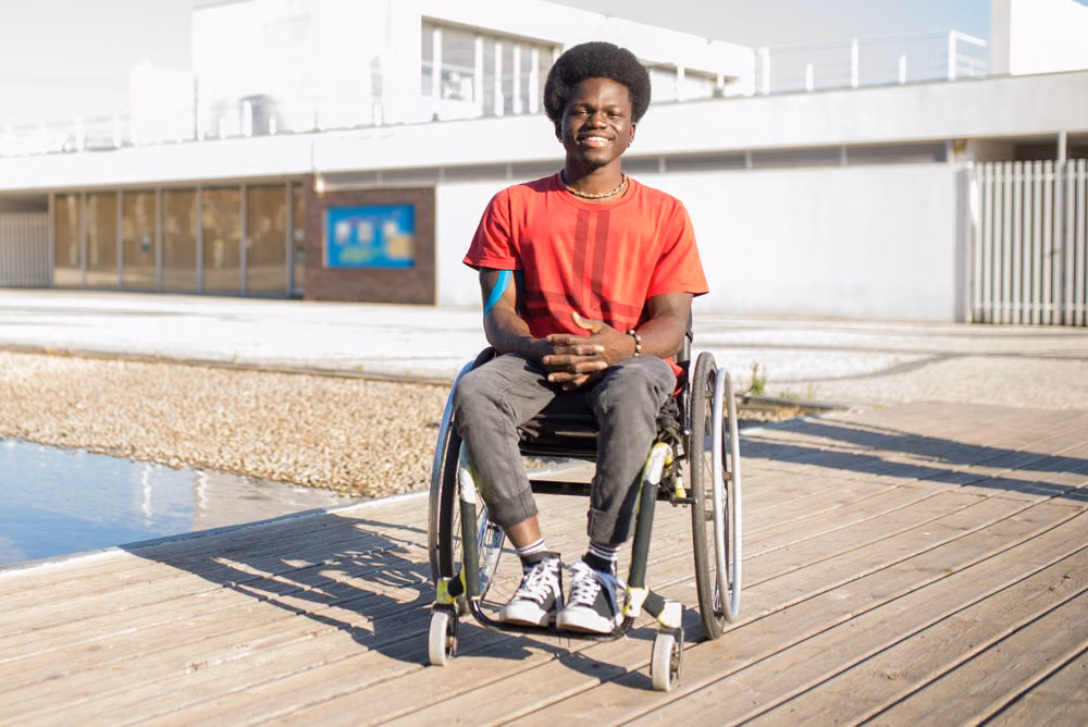 Travailleur handicapé au Togo : jeune homme en fauteuil roulant devant son lieu de travail