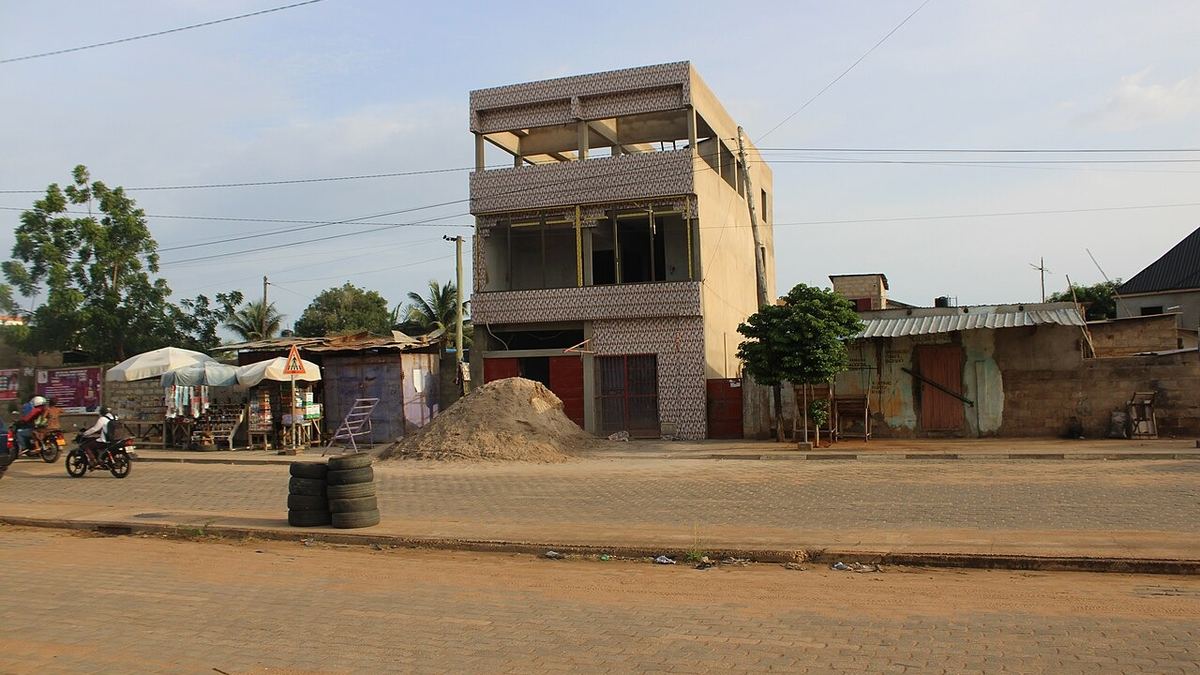 Acheter un terrain au Togo : rue de Lomé avec un immeuble en construction et un tas de sable