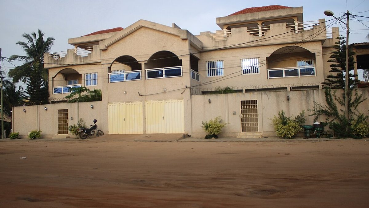 Acheter un terrain au Togo pour y bâtir : villa à étage derrière son mur de clôture, dans une rue en sable de Lomé