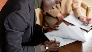 Reçu de vente de terrain au Togo : un homme signe un document à une table