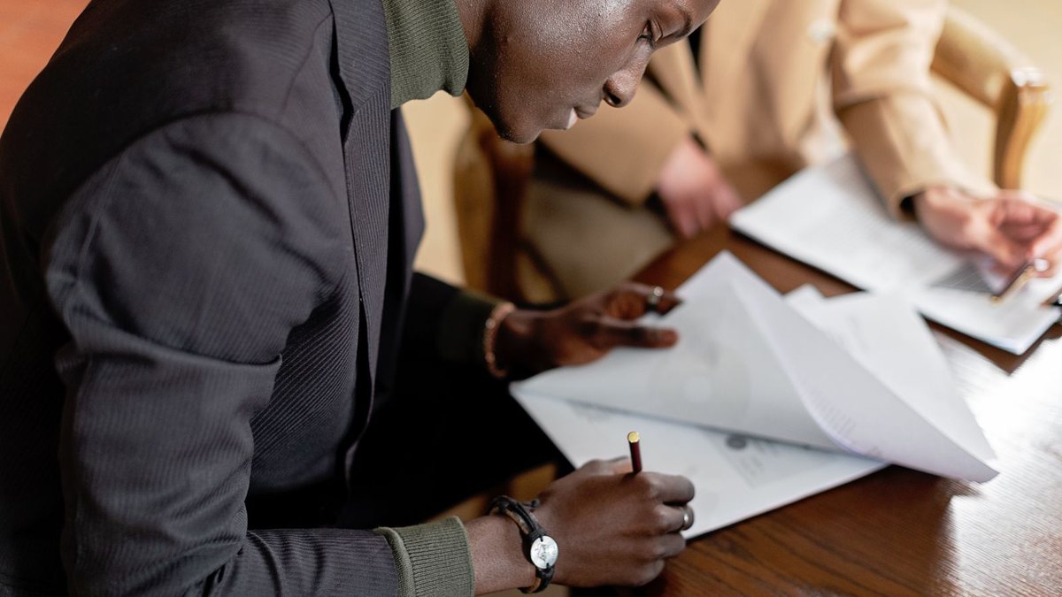 Reçu de vente de terrain au Togo : un homme signe un document à une table