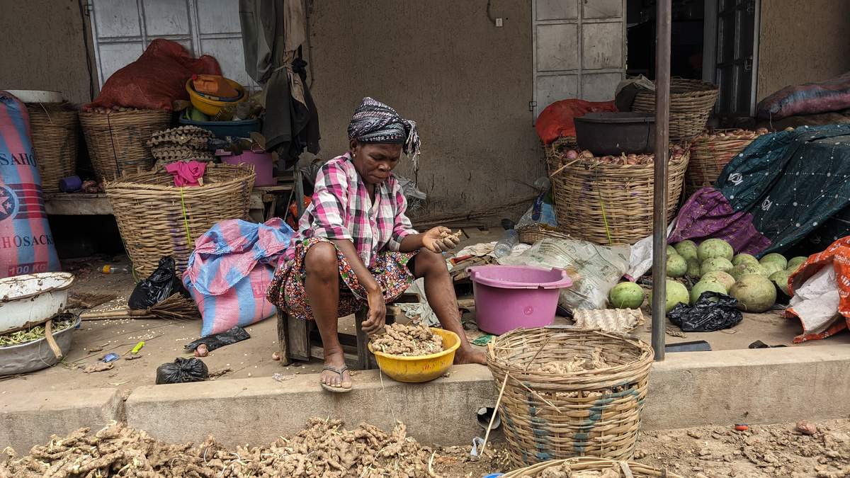 TPU au Togo : vendeuse de gingembre et d’oignons assise devant ses paniers dans un marché de Lomé